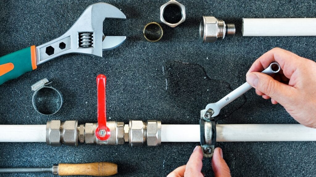 Plumber repairing a pipe valve with an adjustable wrench in Santa Cruz