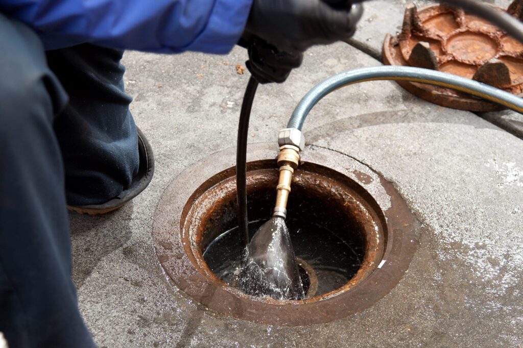 Plumber hydro jetting a sewer line through a manhole in Santa Cruz
