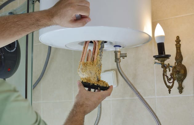 Technician removing mineral buildup from a water heater in Santa Cruz