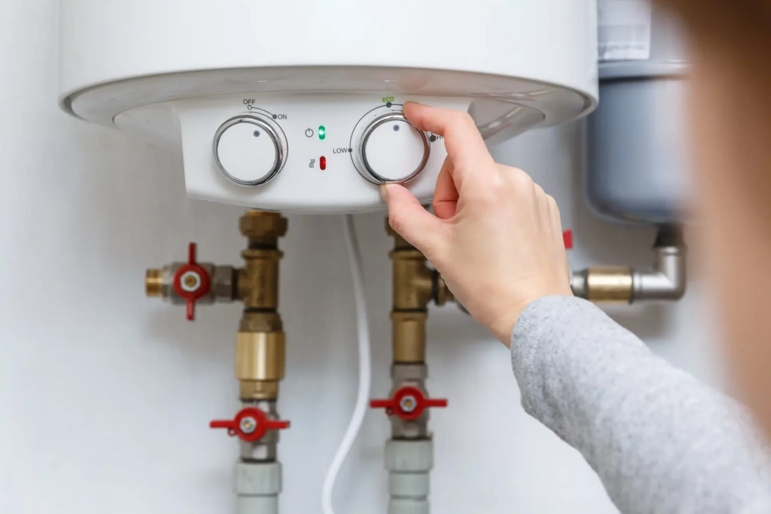 Homeowner adjusting the temperature controls on a water heater in Santa Cruz